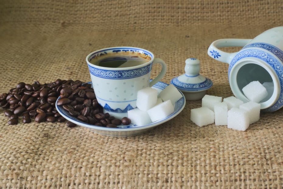 Coffee in a blue and white demitasse with sugar cubes.